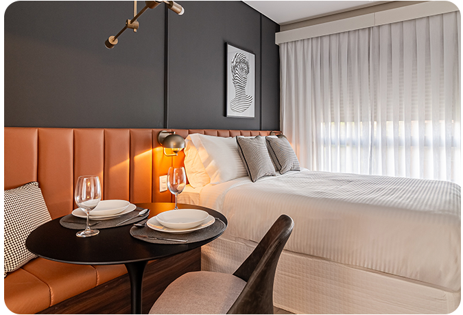 Imagem de um quarto de hotel moderno e confortável com decoração elegante, cama ampla, iluminação suave e vista para o skyline urbano ao fundo, perfeito para hospedagem de lazer ou negócios.