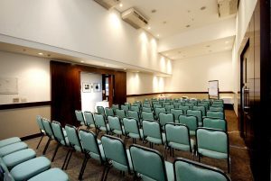Uma sala comercial de eventos de auditório composta por cadeiras verde.
