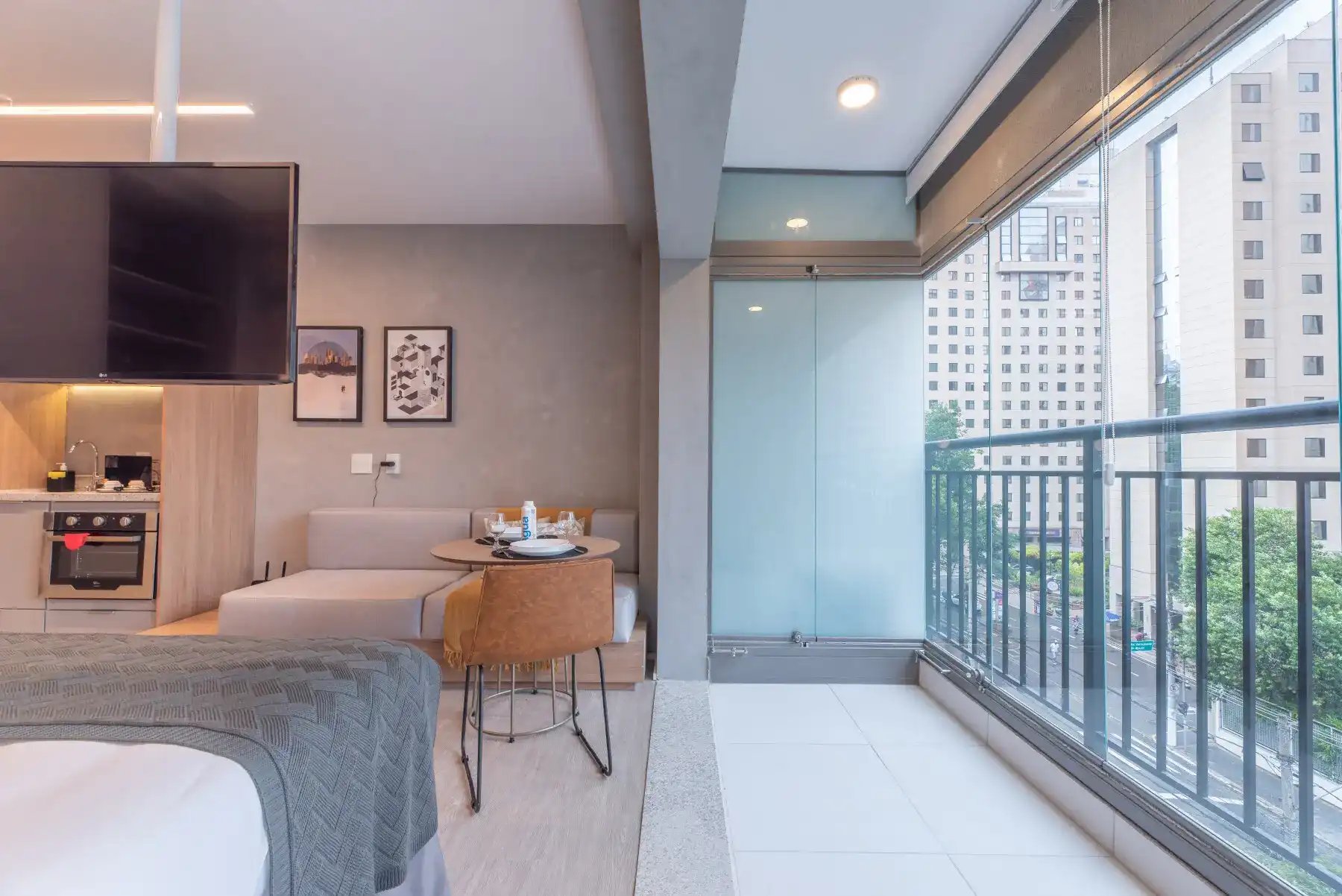 Imagem de sala de estar moderna em um apartamento, com varanda de vidro, vista para prédios altos e decoração minimalista