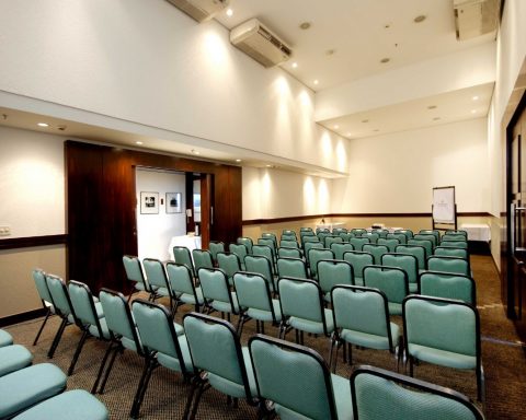Uma sala comercial de eventos de auditório composta por cadeiras verde.
