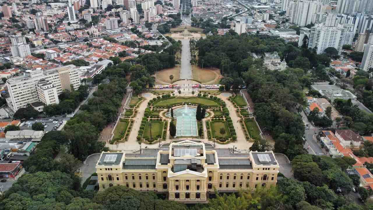 Imagem de um museu em São Paulo com um jardim e árvores ao redor.
