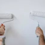 Foto de duas pessoas pintando a parede