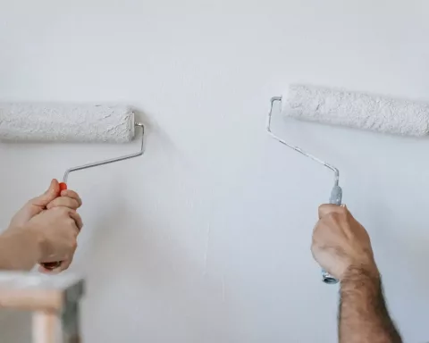 Foto de duas pessoas pintando a parede