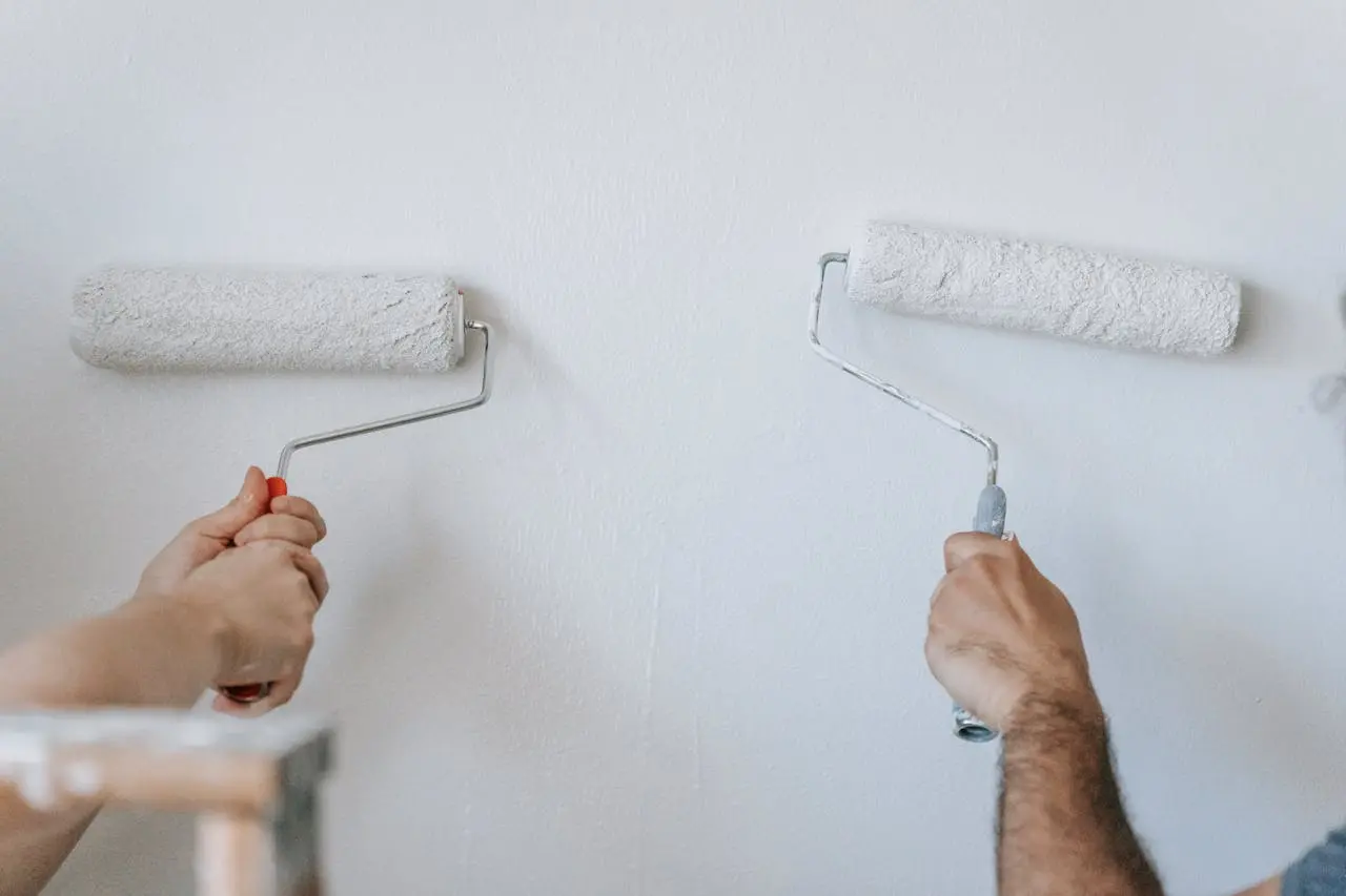 Foto de duas pessoas pintando a parede