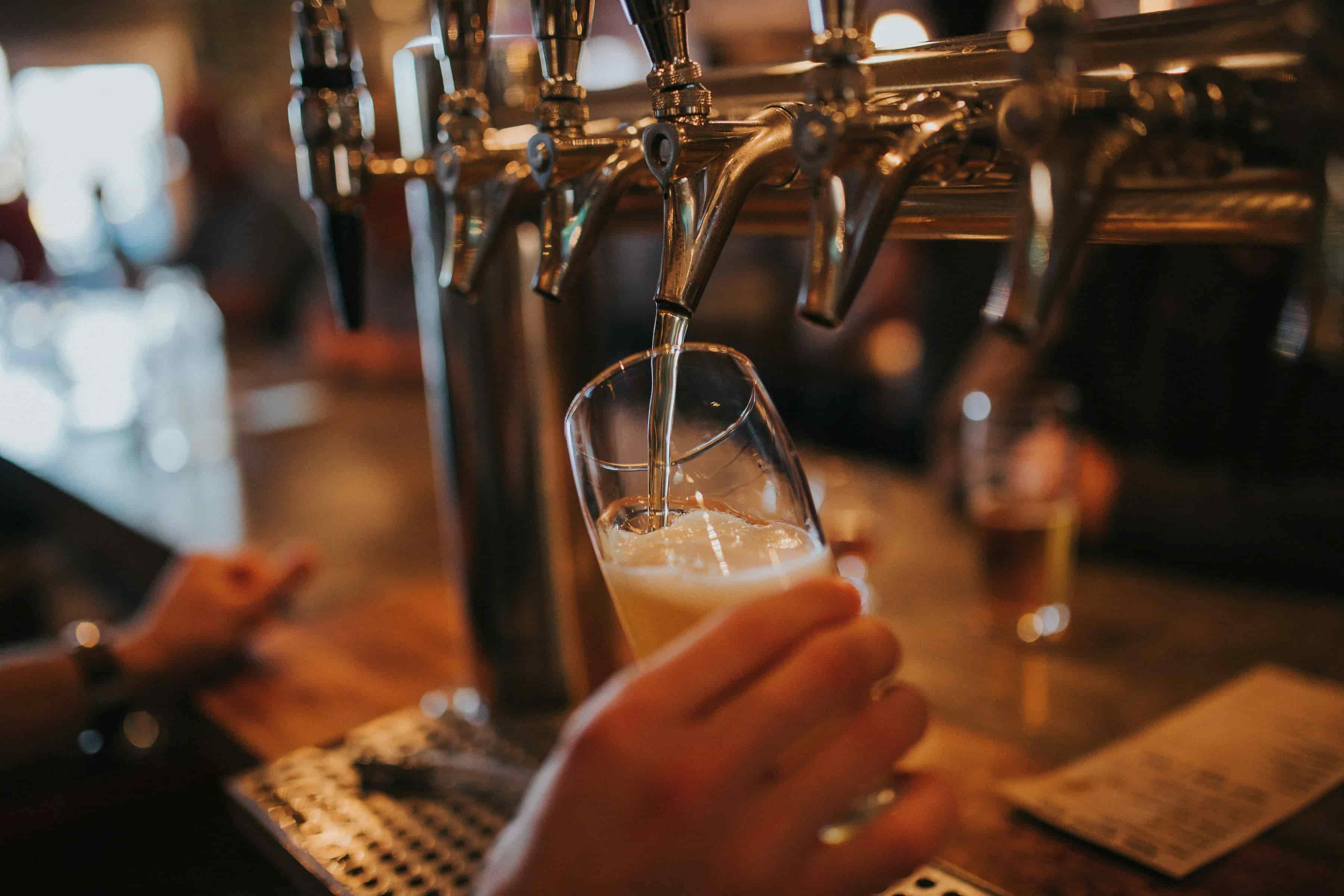 imagem de uma pessoa enchendo o copo de cerveja